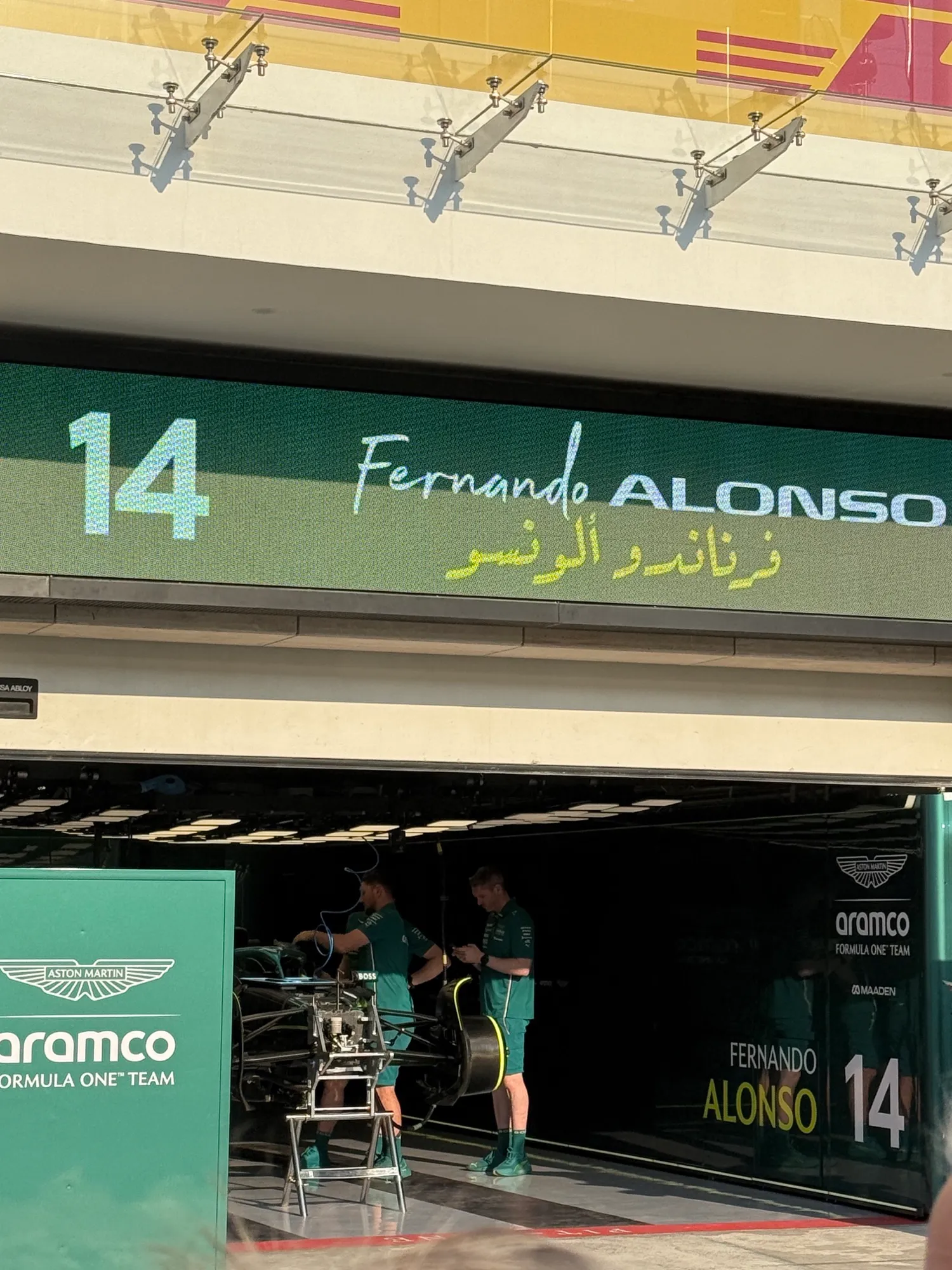 mechanics working on a front wing under fernando alonso’s name board