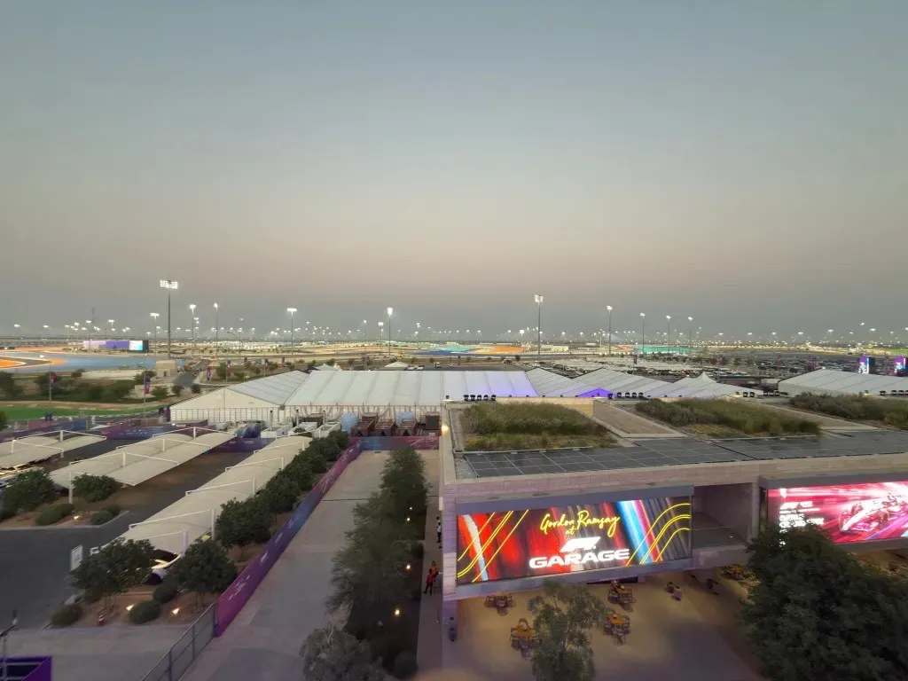 the view from the terrace at dusk, over the fan zone toward the floodlit circuit