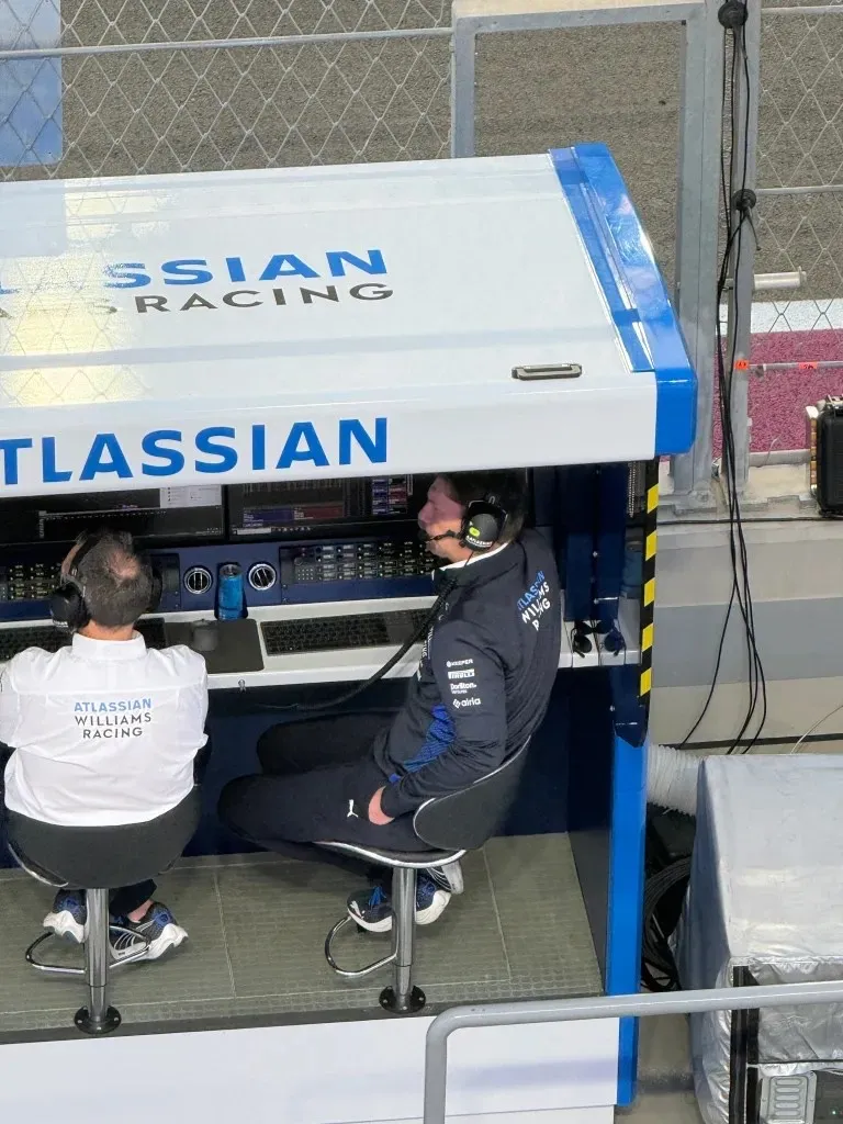 two williams team members wearing headsets on the pit wall, seen from above