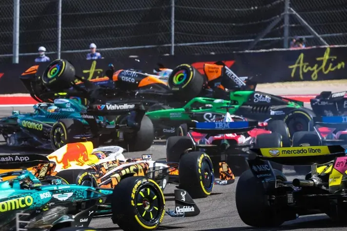 several cars tangled together at the first corner in austin, one mclaren lifted off the ground
