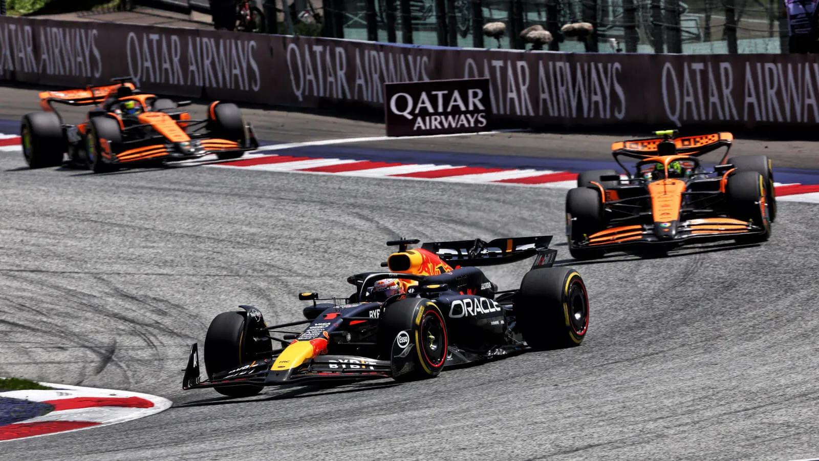 a red bull leads two mclarens through a corner