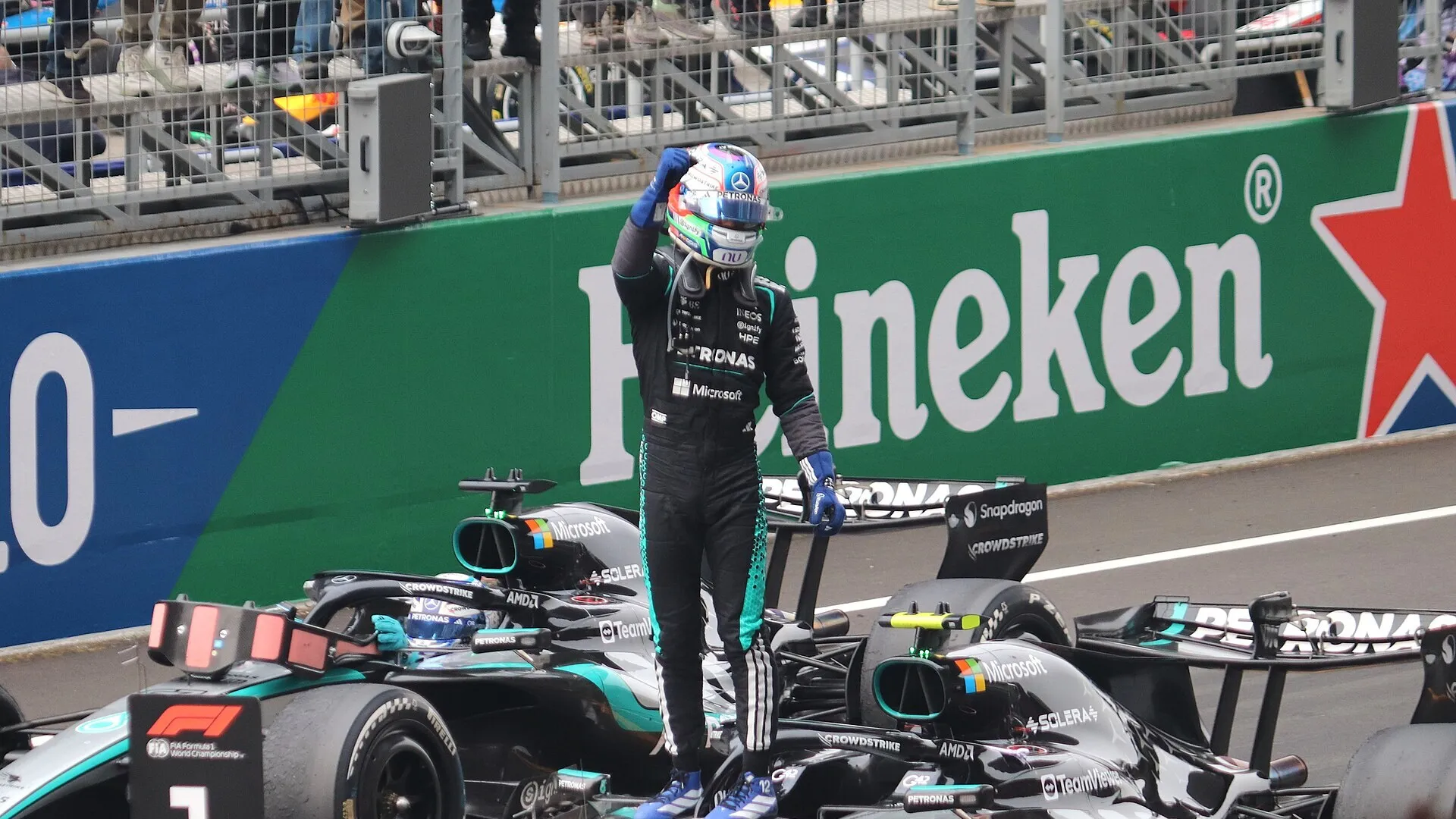kimi antonelli stands on top of his mercedes after a win, next to the number 1 board