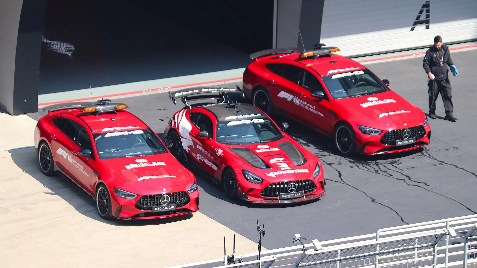 the red F1 safety car parked between two medical cars